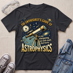 A black graphic t-shirt laid flat on a light beige textured background, styled with clear safety goggles, gray sneakers, and a blue denim jacket. The t-shirt features a detailed graphic of a telescope, planets, stars, and text that reads 'THE ENTHUSIAST'S GUIDE TO ASTROPHYSICS'.