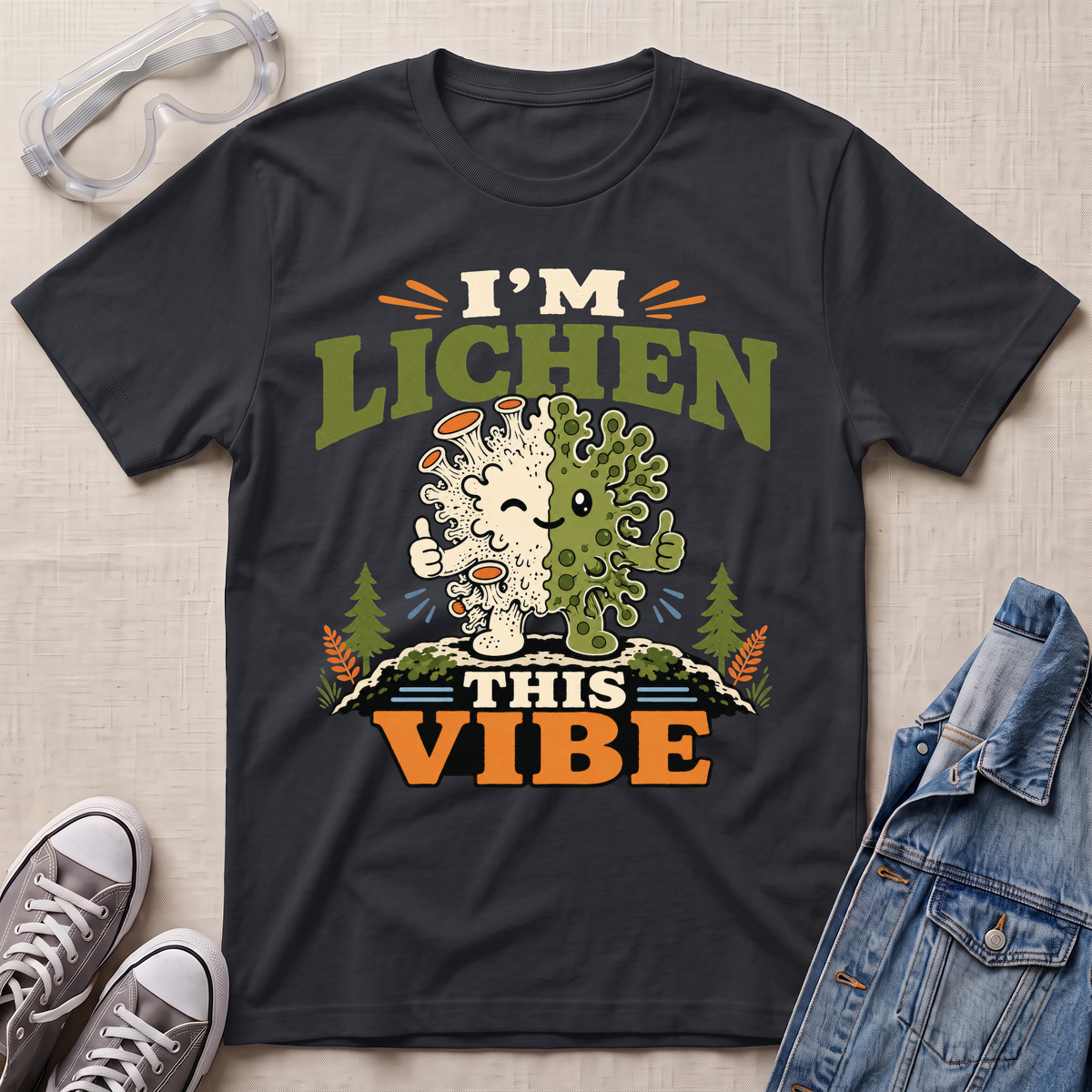 A black science t-shirt featuring a cute lichen character with the pun “I’m Lichen This Vibe,” surrounded by retro botanical and nature-inspired accents.