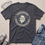 A dark charcoal gray graphic t-shirt featuring a retro circular astronaut design with the text 'TARDIGRADE SPACE EXPLORATION UNIT'. The t-shirt is styled in a flat-lay arrangement on a light beige textured background, accompanied by clear safety goggles, gray sneakers, and a blue denim jacket.