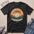 A dark heather gray graphic t-shirt laid flat on a beige textured background, styled with safety goggles, gray sneakers, and a denim jacket. The t-shirt features a retro circular graphic of a smiling fish in ocean waves with the text 'BATHYPELAGIC ZONE' and 'Keep it Deep, Dark, and High Pressure'.