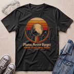 A dark heather gray graphic t-shirt laid flat on a beige fabric background, styled with clear safety goggles, gray sneakers, and a blue denim jacket. The t-shirt features a retro circular design with the moon and stars, and the text 'Pluto: Never Forget 1930-2006'.