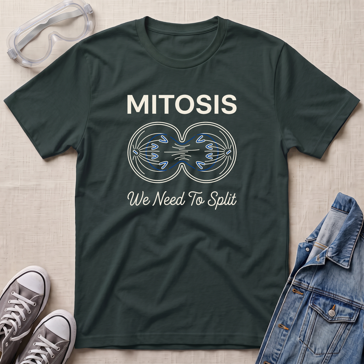A dark green science t-shirt featuring a mitosis cell division diagram with “MITOSIS – We Need To Split” text, styled with lab goggles, sneakers, and a denim jacket.