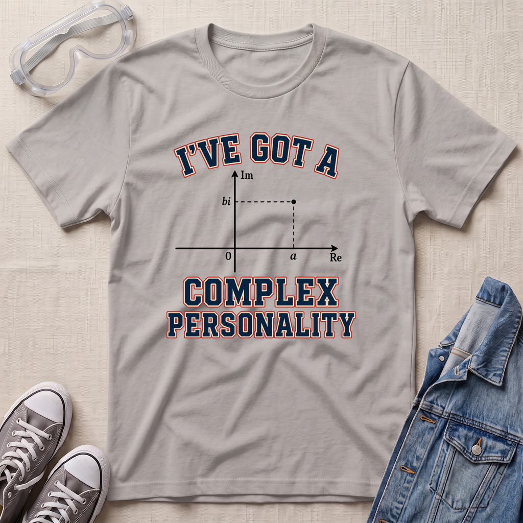 A light gray graphic t-shirt laid flat on a textured beige surface, styled with safety goggles, gray sneakers, and a blue denim jacket. The t-shirt features a graphic of a complex number plot with the text 'I'VE GOT A COMPLEX PERSONALITY' in navy blue with a red outline.