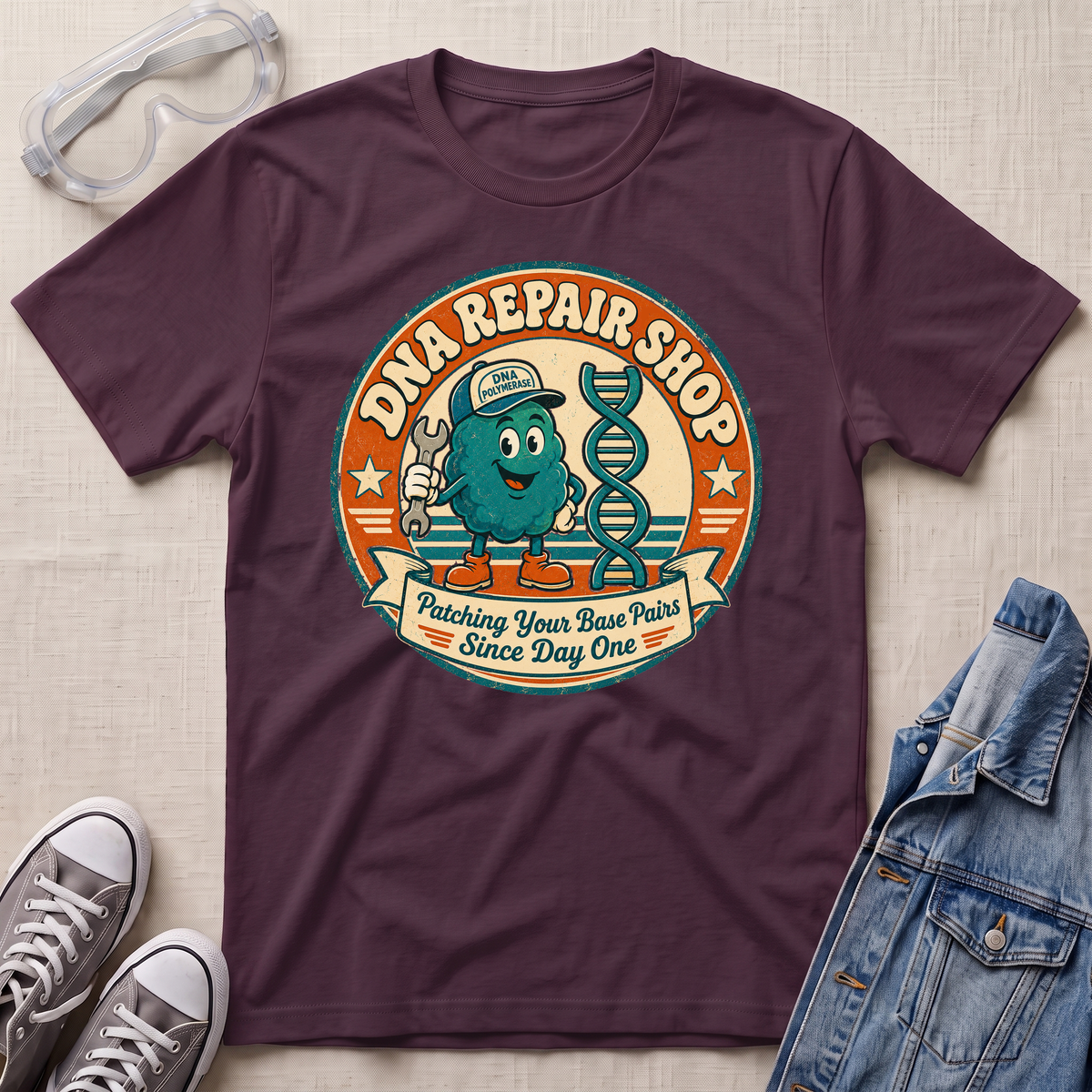 A dark plum purple graphic t-shirt laid flat on a light beige textured background, styled with safety glasses, gray sneakers, and a blue denim jacket. The t-shirt features a retro circular graphic for 'DNA REPAIR SHOP' with a cartoon teal DNA helix character.