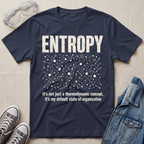 A navy blue graphic t-shirt laid flat on a beige fabric background, styled with safety goggles, gray sneakers, and a denim jacket. The t-shirt features a white distressed graphic of the word 'ENTROPY' above a entropy pattern, with the text 'It's not just a thermodynamic concept, it's my default state of organization' below.