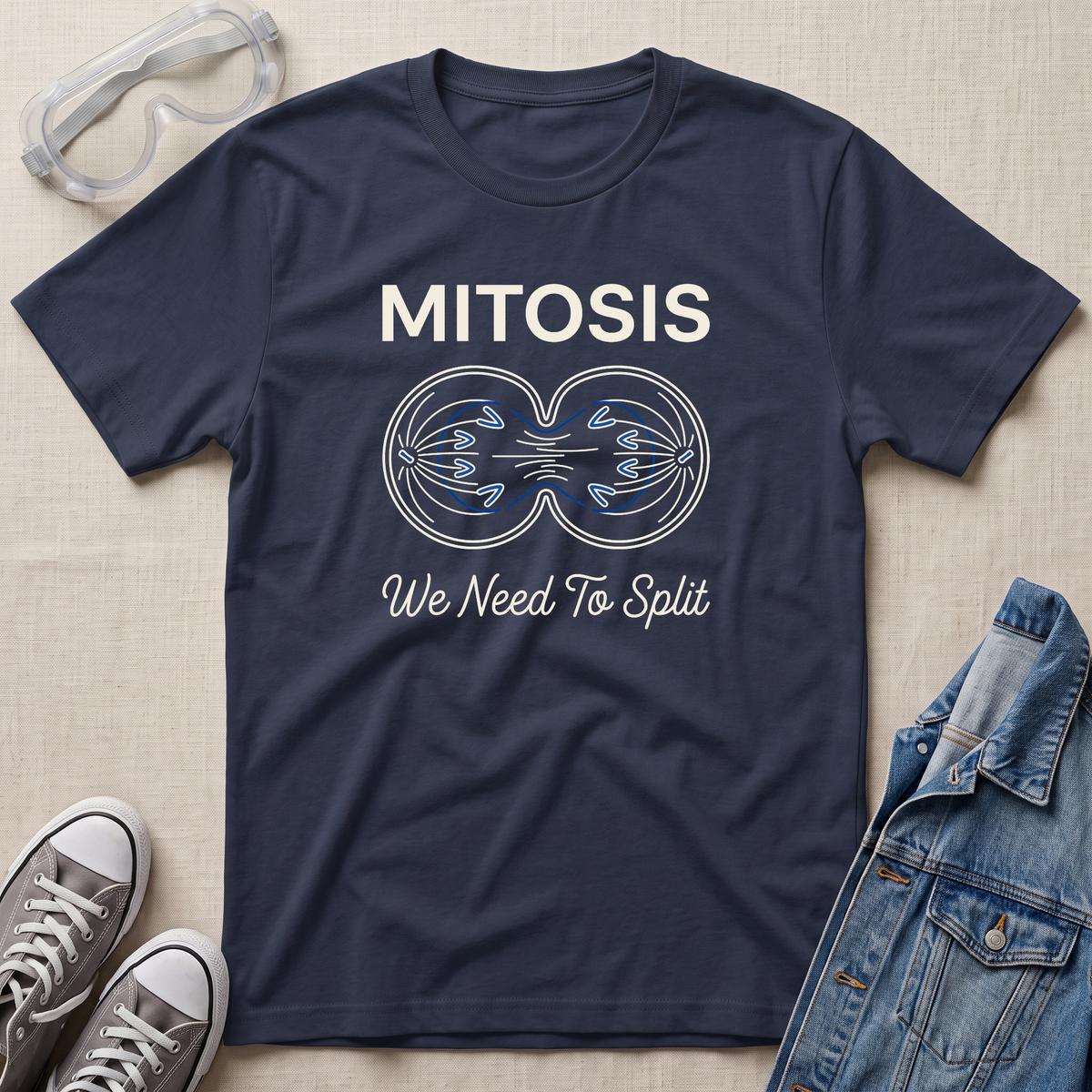 A navy blue science t-shirt featuring a mitosis cell division diagram with “MITOSIS – We Need To Split” text, styled with lab goggles, sneakers, and a denim jacket.