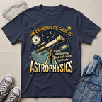 A navy blue graphic t-shirt laid flat on a light beige textured background, styled with safety goggles, gray sneakers, and a denim jacket. The t-shirt features a detailed space-themed graphic with a telescope, planets, stars, and the text 'THE ENTHUSIAST'S GUIDE TO ASTROPHYSICS' in a bold yellow font.