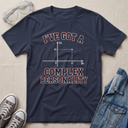 A navy blue graphic t-shirt laid flat on a beige fabric background, styled with safety goggles, gray sneakers, and a denim jacket. The t-shirt features a graphic of a complex number magnitude plot with the text 'I'VE GOT A COMPLEX PERSONALITY' in white with a red outline.