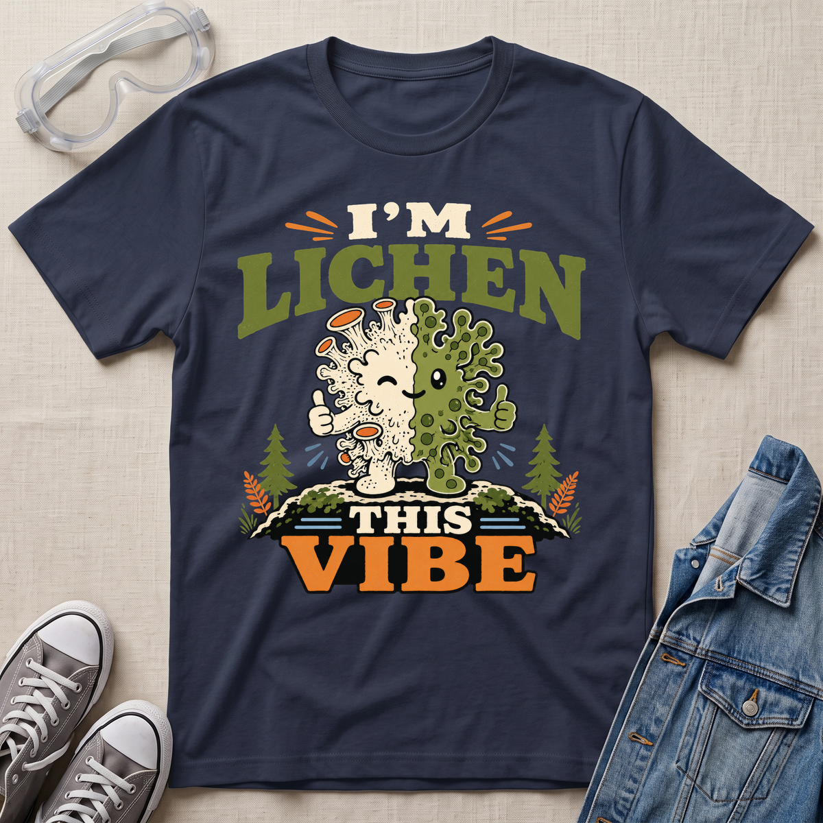 A navy blue science t-shirt featuring a cute lichen character with the pun “I’m Lichen This Vibe,” surrounded by retro botanical and nature-inspired accents.
