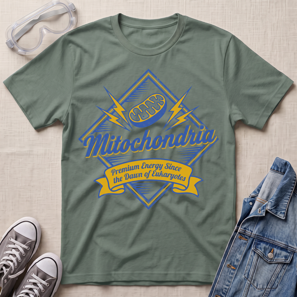 An olive green graphic t-shirt featuring a blue and yellow 'Mitochondria' design, styled in a flat-lay with safety goggles, sneakers, and a denim jacket on a textured beige background.