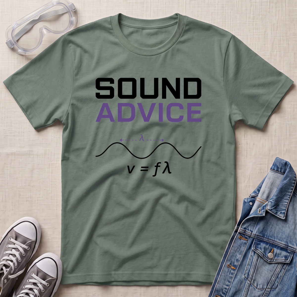An olive green graphic t-shirt laid flat on a textured beige surface, surrounded by lifestyle props including clear safety goggles, gray sneakers, and a blue denim jacket. The t-shirt features the text 'SOUND ADVICE' in black and purple, with a black wave equation graphic below.