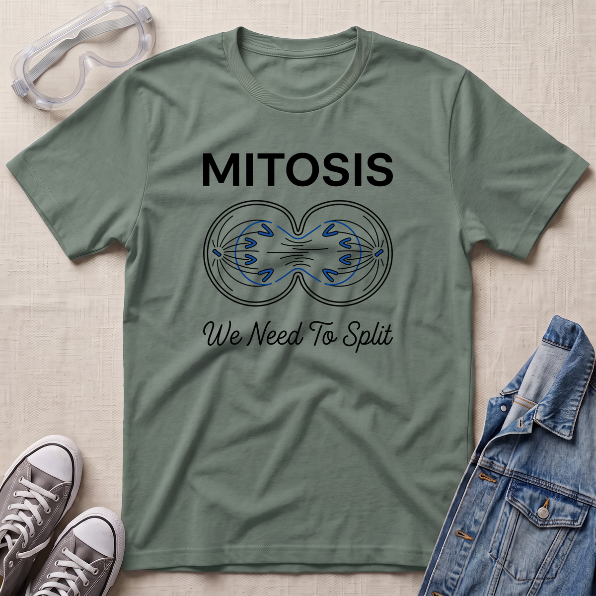 A sage green science t-shirt featuring a mitosis cell division diagram with “MITOSIS – We Need To Split” text, styled with lab goggles, sneakers, and a denim jacket.