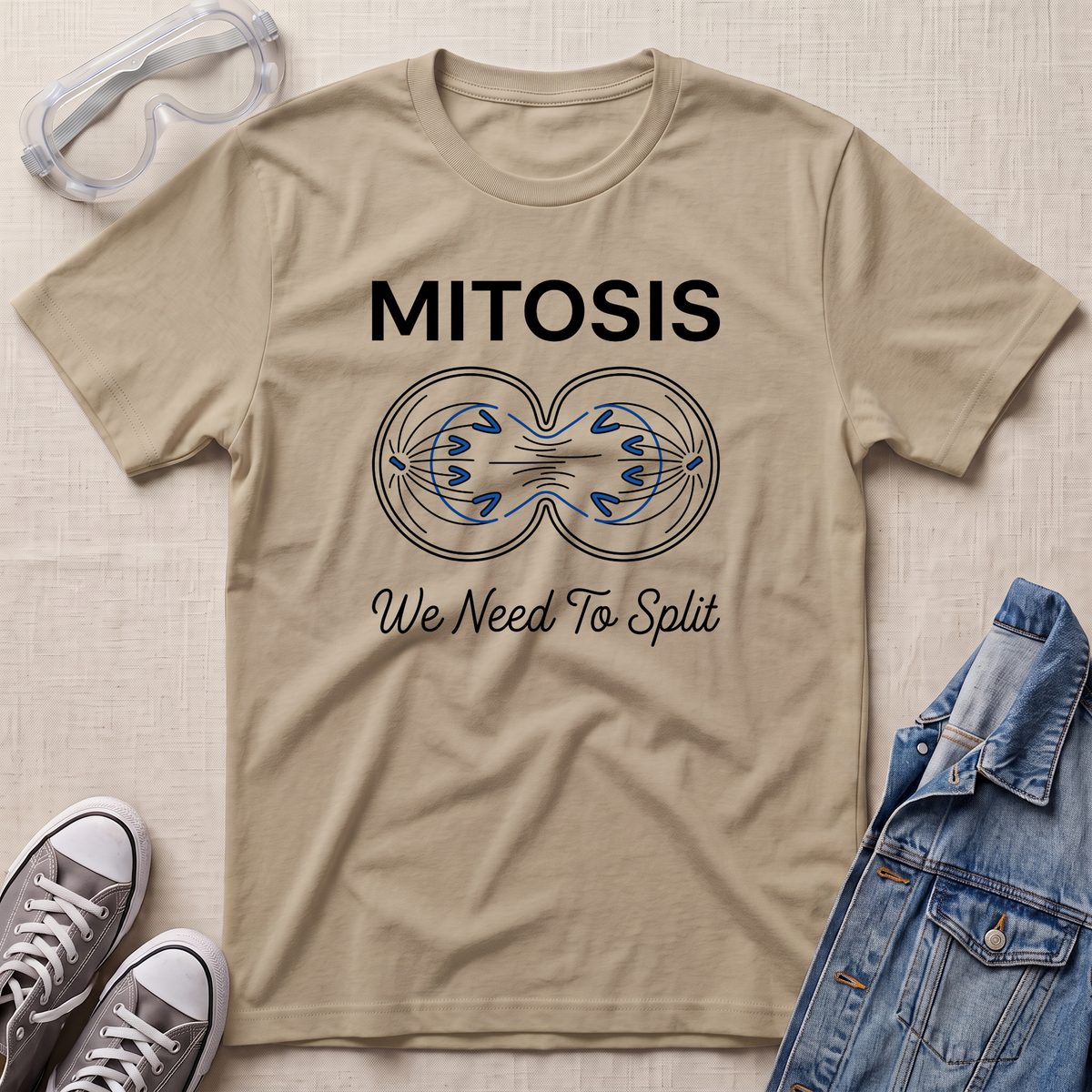 A beige science t-shirt featuring a mitosis cell division diagram with “MITOSIS – We Need To Split” text, styled with lab goggles, sneakers, and a denim jacket.