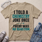 A beige graphic t-shirt with the text 'I TOLD A CHEMISTRY JOKE ONCE THERE WAS NO REACTION' in black and teal lettering, styled in a flat-lay with safety goggles, gray sneakers, and a denim jacket on a textured beige background.