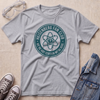A heather gray t-shirt with a teal circular graphic reading 'HEISENBERG FAN CLUB' and 'WE'RE NOT CERTAIN WE'RE HERE.' surrounded by an atom symbol.