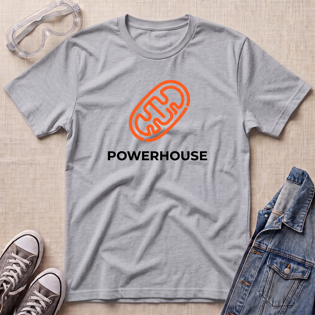 A heather gray short-sleeve t-shirt with an orange mitochondrial outline and the word 'POWERHOUSE' printed in black on the chest, styled in a flat lay with safety goggles, sneakers, and a denim jacket on a light beige textured background.