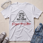 A white graphic t-shirt laid flat on a light beige textured background, styled with safety goggles, gray sneakers, and a denim jacket. The t-shirt features a black bell curve graphic with the text 'AVOID THE TOP OF THE BELL CURVE' and 'Everyone there is Mean' in red script.
