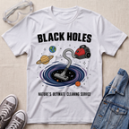 A white graphic t-shirt laid flat on a textured fabric background, styled with safety goggles, sneakers, and a denim jacket. The t-shirt features a cartoon illustration of a vacuum cleaner falling into a black hole surrounded by planets, with the text 'BLACK HOLES' and 'NATURE'S ULTIMATE CLEANING SERVICE'.