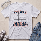 A white graphic t-shirt laid flat on a beige textured surface, styled with safety goggles, gray sneakers, and a denim jacket. The t-shirt features a graphic of a complex plane with the text 'I'VE GOT A COMPLEX PERSONALITY' in navy blue with a red outline.